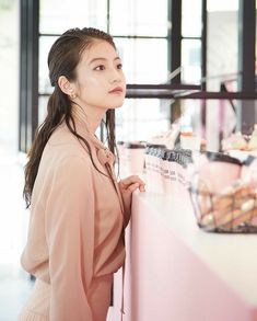 a woman standing in front of a counter with donuts on it's sides