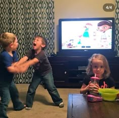 three children playing with toys in front of a tv