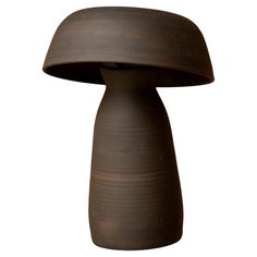 a brown vase sitting on top of a white table next to a black object in the shape of a mushroom