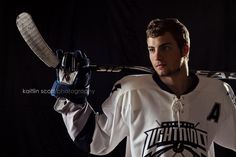 a man holding a hockey stick and wearing a white jersey with the number 4 on it