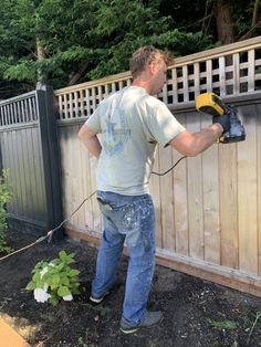 a man using a power drill on a fence