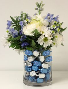 a glass vase filled with blue and white flowers next to marshmallows on a table