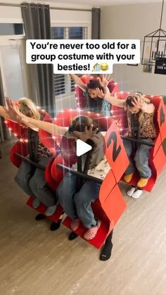 three people sitting on top of red chairs with their arms in the air and one person standing behind them