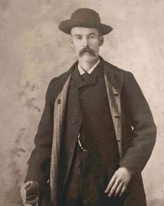 an old black and white photo of a man with a mustache wearing a suit and hat