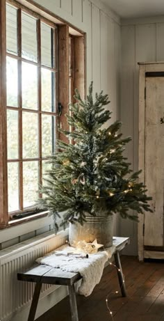 a small christmas tree sitting on top of a wooden table in front of a window