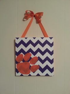 an orange ribbon hanging on a wall with a chevron pattern and paw prints painted on it