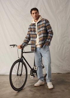 Stay effortlessly cool this fall with a layered plaid shirt over a cozy hoodie, paired with light-washed jeans for a laid-back yet stylish look. Perfect for biking through the city or a casual day out, this outfit blends comfort and style seamlessly. Complete the ensemble with classic white sneakers for that clean, fresh touch. Ideal for urban explorers who love keeping it relaxed yet fashionable. # Mens Fall Outfits, Plaid Shirt Outfits, Hoodie Outfit Men, Jeans Outfit Men, Flannel Outfits, Outfits Hombre, Fall Outfits Men, Winter Outfits Men, Mens Fashion Fall