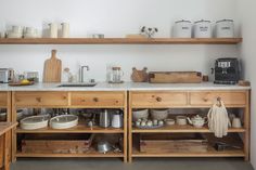 a kitchen with lots of wooden shelves and dishes on top of the countertop,