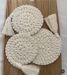 three crocheted coasters with tassels on a wooden board