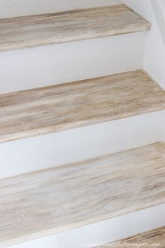 three wooden steps with white walls and wood flooring on the bottom one is empty