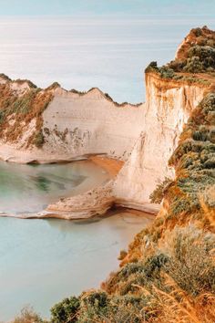 a large body of water sitting next to a white cliff on top of a hill