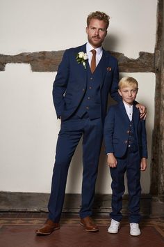 a man in a blue suit with his arm around a little boy wearing a white shirt and tie