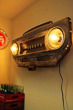 an old car headlight mounted on the wall next to a red box filled with bottles