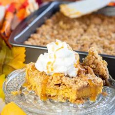 a close up of a slice of pie on a plate with whipped cream and autumn leaves in the background