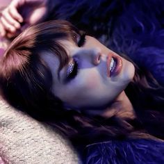 a woman laying on top of a purple blanket