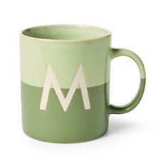 a green and white mug with the letter m on it