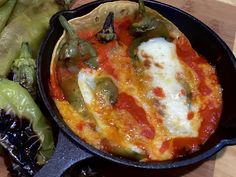 an omelet in a cast iron skillet next to green peppers