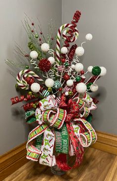 a vase filled with candy canes and christmas decorations on top of a wooden floor