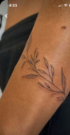 a woman's arm with a tattoo on it that has leaves growing out of it