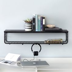 a laptop computer sitting on top of a desk next to a book shelf filled with books