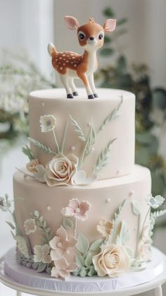 a three tiered cake decorated with flowers and a deer figurine on top