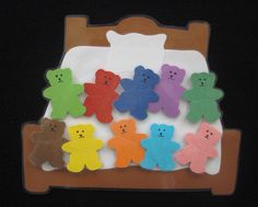 a bunch of small teddy bears on a bed with a black background and brown wooden headboard