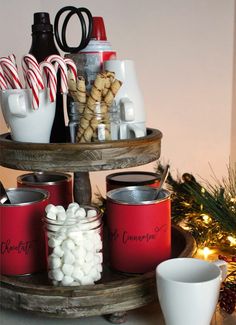 a three tiered tray with candy canes, hot chocolate and marshmallows