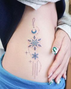 a woman's stomach with a snowflake tattoo on her lower back and side