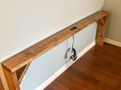 a wooden bench sitting on top of a hard wood floor next to a white wall