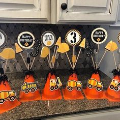 an assortment of construction themed cupcake toppers on a kitchen counter with orange cones