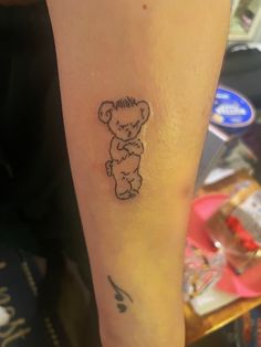 a small tattoo on the arm of a person with a teddy bear in black ink