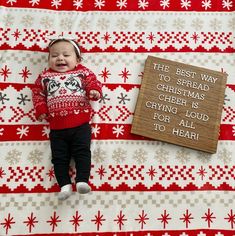 a baby laying on top of a blanket next to a wooden sign that says the best way to spread christmas cheer is crying loud for all to hear