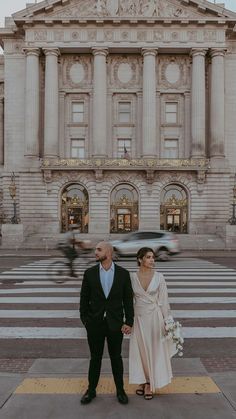 a man and woman standing in front of a building with a car passing by them