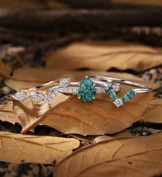 three rings with turquoise stones and diamonds on top of leaves in the woods by manhattan box