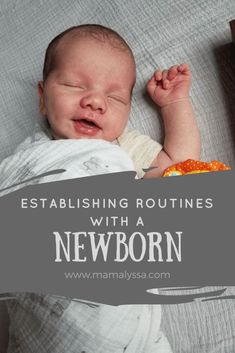 a baby laying on top of a bed next to a wooden box with an orange slice in it