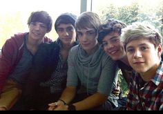 several young men are posing for a photo in front of a window with their arms around each other