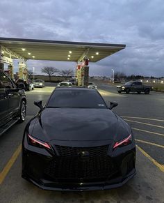 a black sports car parked in front of a gas station at dusk with the lights on