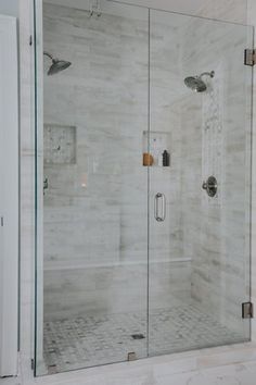 a walk in shower sitting next to a white wall and floor covered in marble tiles