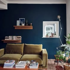 a living room with blue walls and green couches in front of bookshelves