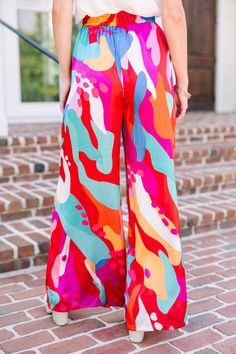 I mean, wow! These wide leg pants are stunning! Those colors and that print are so wonderfully bold! These pants are truly the star of the show so we would recommend pairing them with a solid tank or sleeveless blouse so that you can really let them shine! These pants feature an elastic waist with drawstring detail, wide legs, satin fabric, and a bold and colorful abstract print. Material has no amount of stretch however the elastic extends the waist. Baileigh is wearing the small. Summer Bold Print Multicolor Pants, Multicolor Wide Leg Bottoms With Vibrant Print, Drop Sleeve Sweater, Multicolor Wide-leg Pants With Bold Print, Red Wide-leg Pants With Elastic Waistband, Light Blue Cardigan, Multicolor Graphic Print Wide-leg Bottoms, Hot Pink Leopard, Babies Nursery