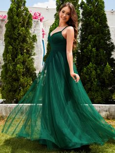 a woman in a long green dress posing for the camera with her hand on her hip