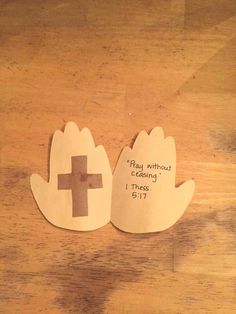 two paper cutouts depicting hands and a cross