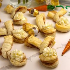 small pastries are arranged on a table with carrots and other food items in the background