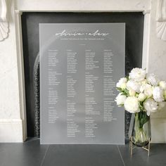 a vase with white flowers sitting on top of a table next to a large sign