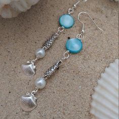 ~BEACHY~ ~Silver plated Earrings with ocean themed beads~The perfect gift for someone who loves the beach!*Drop earrings which are approximately one and a half inches long.*These earrings are made with silver-plated fish hooks for PIERCED ears.*These earrings are made from silver plated shell charms, glass pearls, fish beads, and blue mother of pearl beads.CARE*They are made from silver plated components.  *Exposure to air speeds up the tarnishing process.*To keep it from tarnishing, do not get Silver Ocean-inspired Earrings, Nickel-free Silver Ocean-inspired Earrings, Ocean-inspired Silver Jewelry With Matching Earrings, Handmade Mermaid Earrings For Gift, Ocean-inspired Sterling Silver Dangle Earrings, Silver Dangle Pearl Earrings For Beach, Nickel-free Ocean-inspired Dangle Jewelry, Ocean-inspired Sterling Silver Jewelry With Ear Wire, Nickel-free Ocean-inspired Dangle Earrings