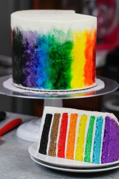 there is a rainbow cake with white frosting on the top and bottom, next to a half - eaten rainbow cake