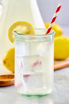 a glass filled with ice and a straw next to lemons