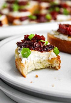 two pieces of bread with cranberry toppings on them sitting on white plates