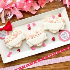 two decorated cookies sitting on top of a white plate next to pink and red streamers