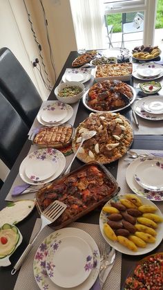 a long table filled with lots of plates and food on top of each other in front of a window